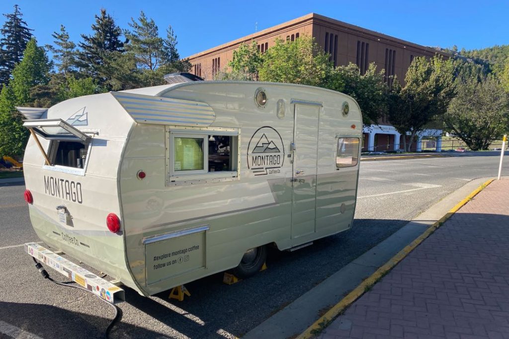White and green vintage travel trailer with the name Montago Coffee Company on the side.