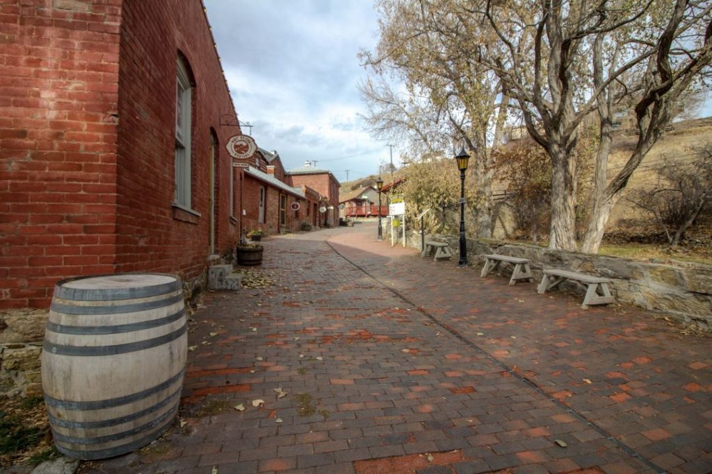 Cobblestone street with wooden barrel in the foreground and historic red brick buildings lining the street.