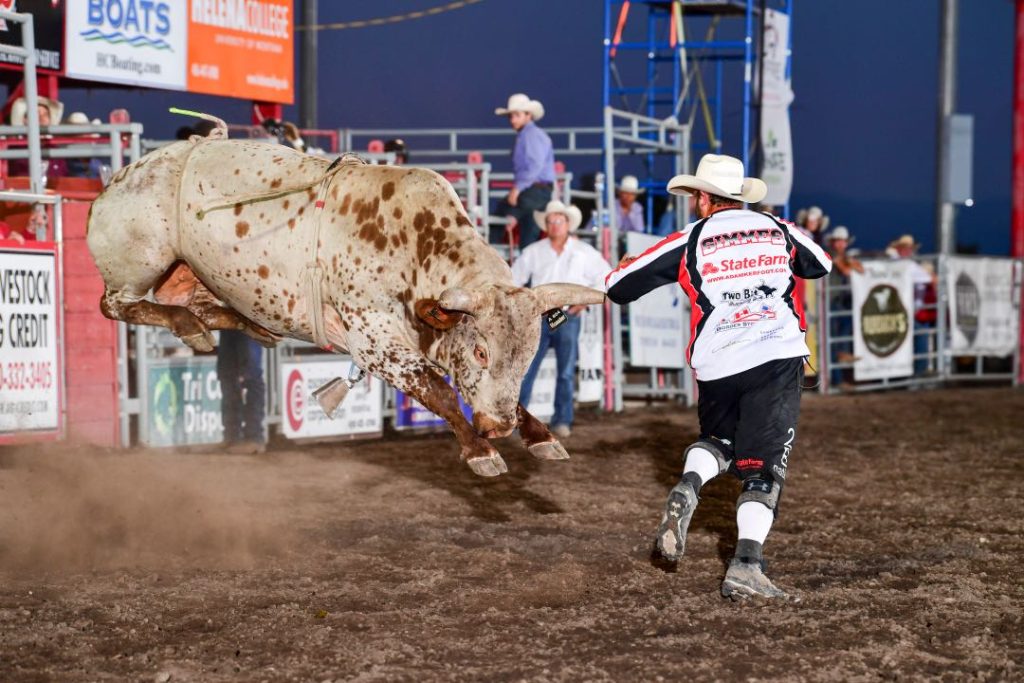 A bull launches into the air as a rider quickly moves out of the way.