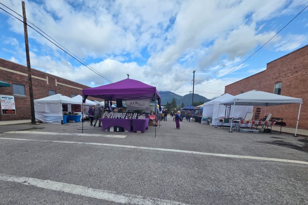 A closed-off city street with multiple tables with awnings selling jams and produce.