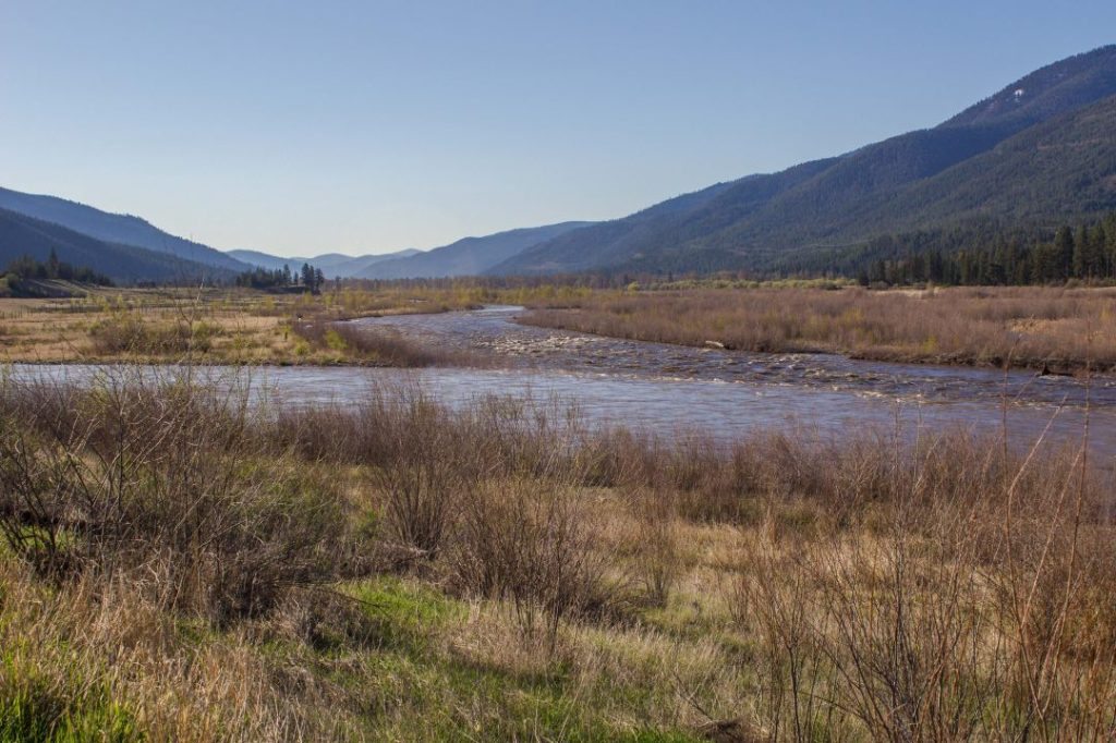 Two rivers come together in a wide, grassy valley.