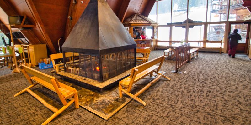 A fireplace surrounded by log benches in a ski lodge