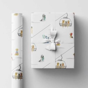 A roll of white wrapping paper with dogs on a ski lift printed on it. Also a box wrapped in that paper.