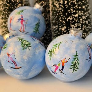 Three glass ball ornaments with hand-painted skiers and trees on them.