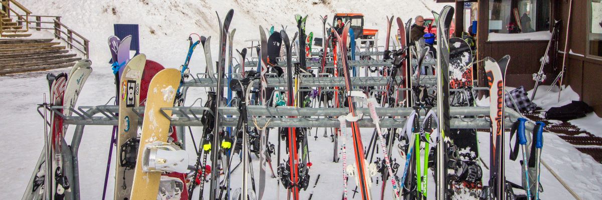Racks of skis and snowboards outside a ski lodge.